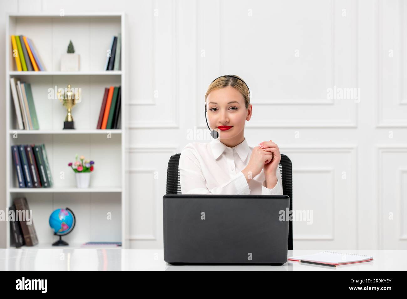 customer service cute blonde girl in office shirt with headset and computer smiling and greeting Stock Photo
