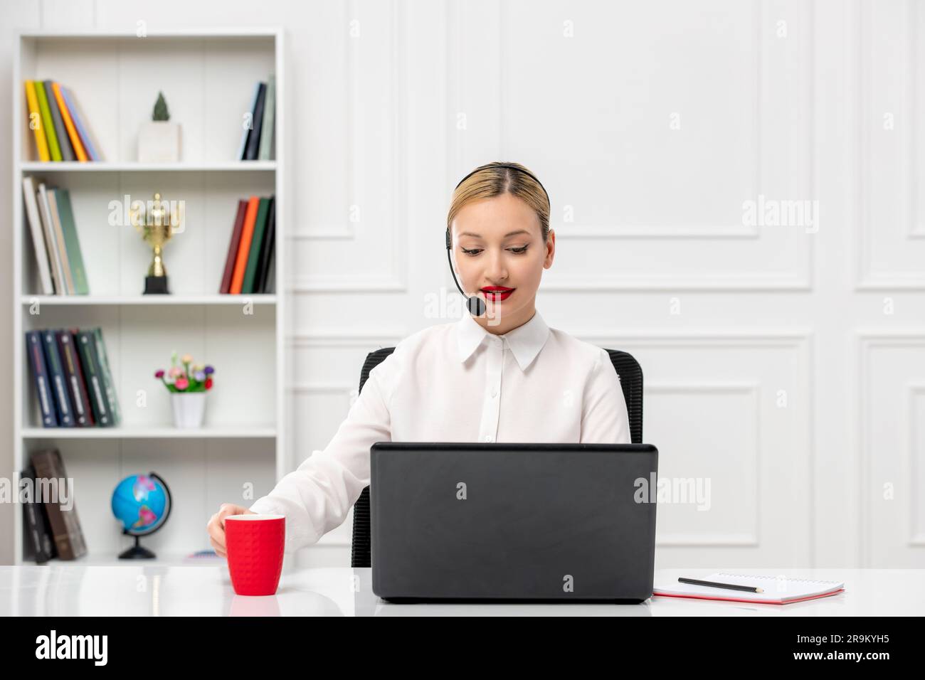 customer service cute blonde girl office shirt with headset and computer holding a red cup Stock Photo