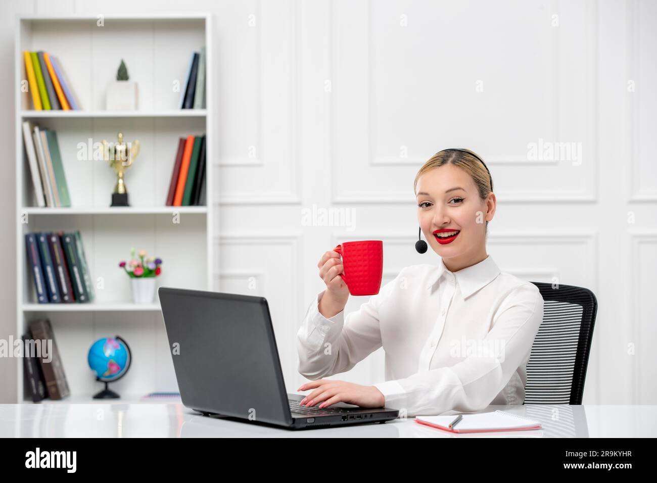 customer service cute blonde girl office shirt with headset and computer holding red cup Stock Photo
