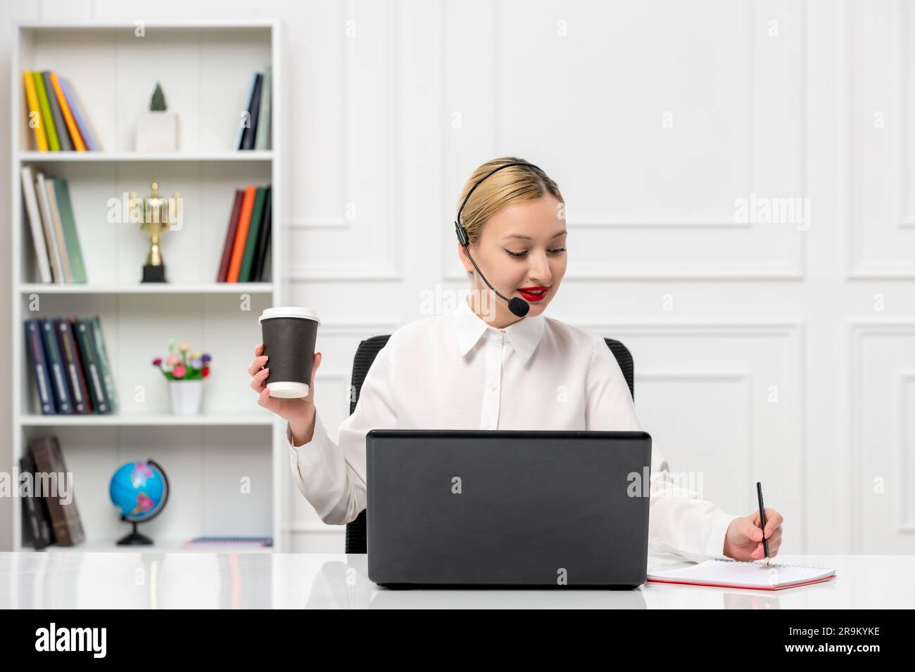 customer service cute blonde girl office shirt with headset and computer taking down notes Stock Photo