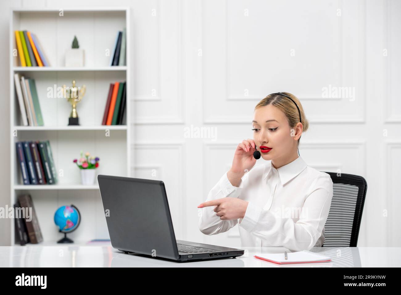 customer service cute blonde girl office shirt with headset and computer talking to a client Stock Photo