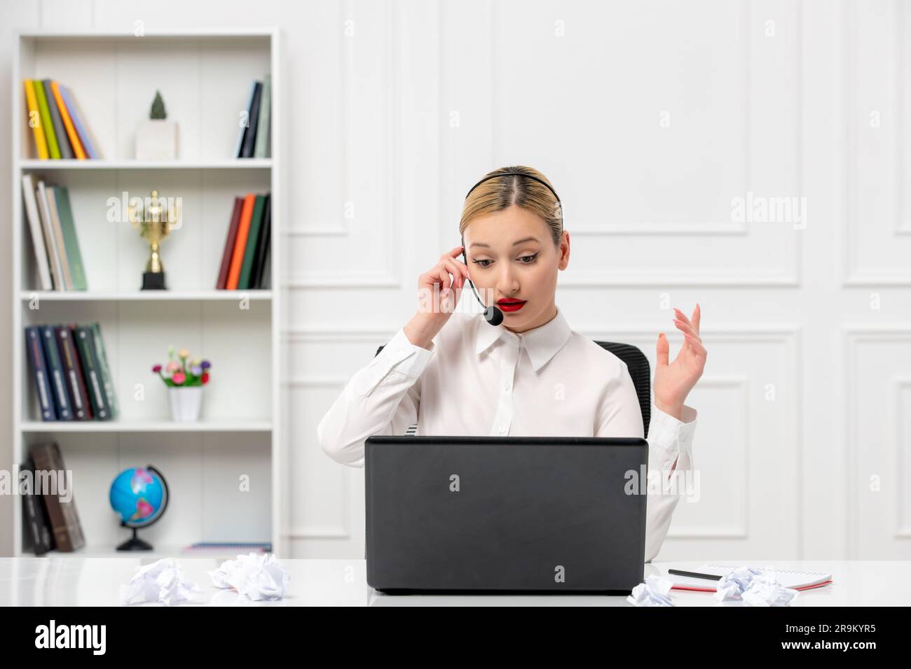 customer service cute blonde girl office shirt with headset and computer wondering on the phone Stock Photo