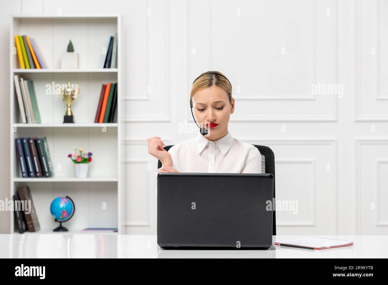 customer service cute woman in white shirt with headset and computer confused looking down Stock Photo