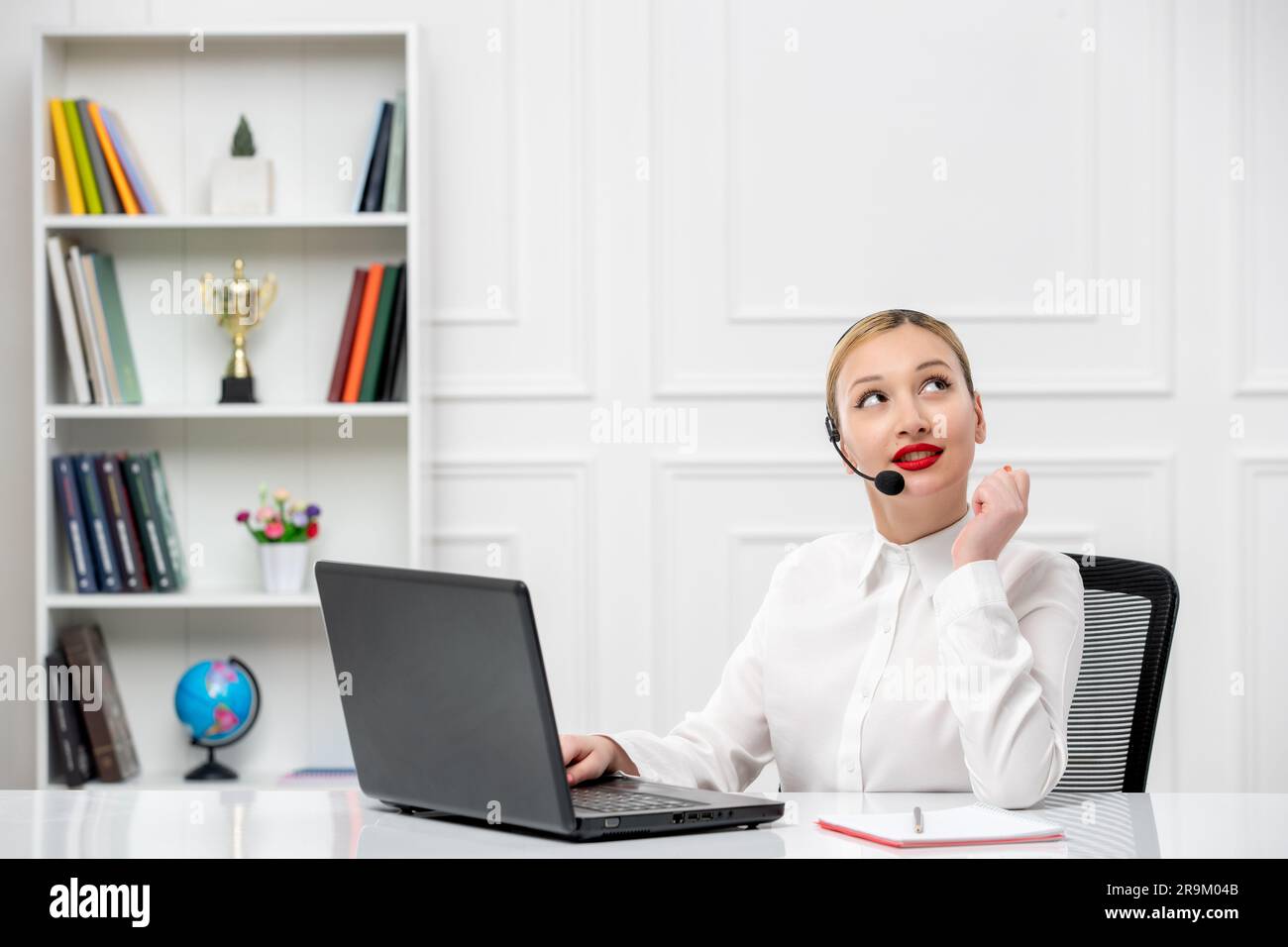 customer service cute blonde girl office shirt with headset and computer looking up and smiling Stock Photo