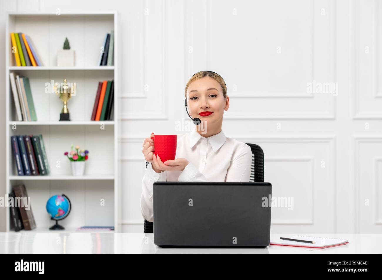 customer service cute blonde girl office shirt with headset and computer holding a red cup Stock Photo