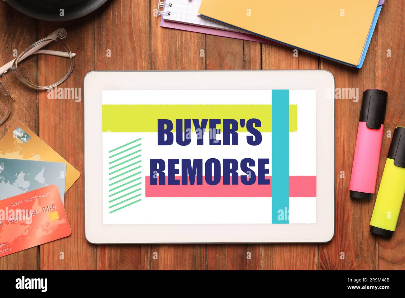 Tablet with text Buyer's Remorse, credit cards and stationery on wooden table, flat lay Stock Photo