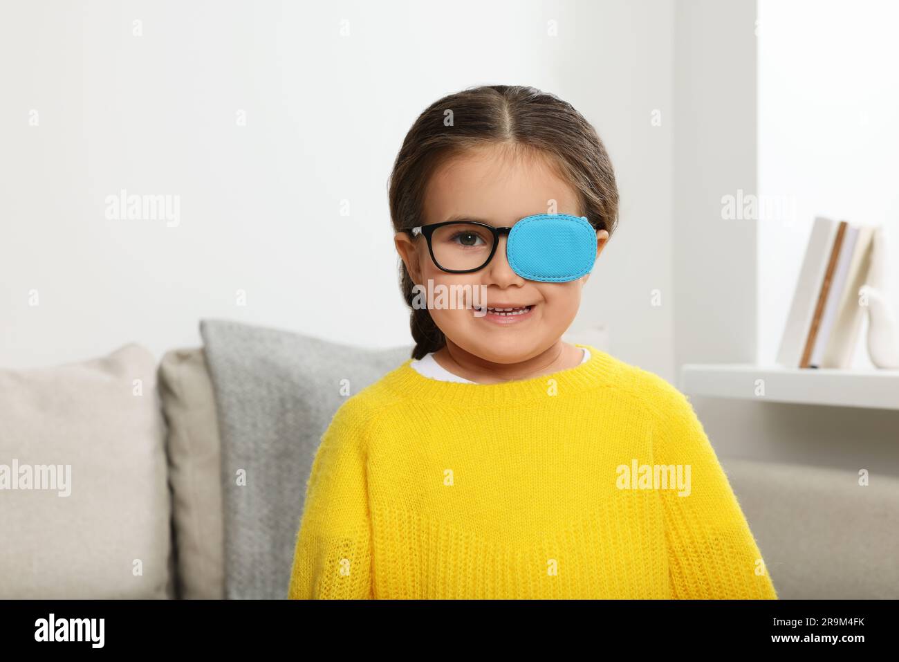 Happy girl with nozzle on glasses for treatment of strabismus in room