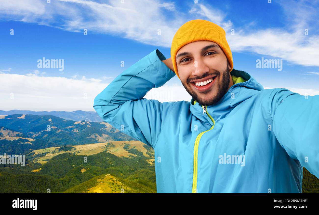Smiling young man taking selfie in mountains Stock Photo