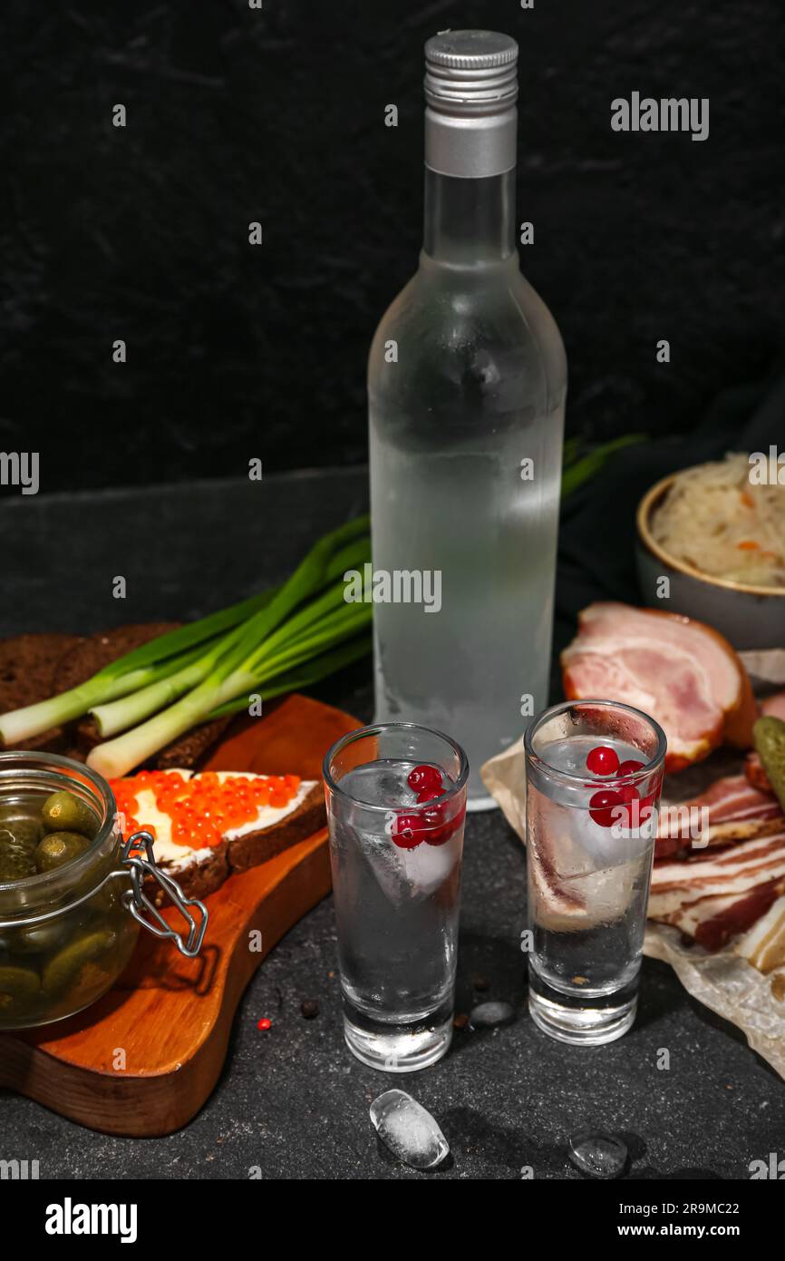 Shots and bottle of cold vodka with snacks on black background Stock ...