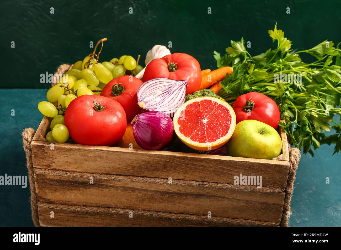 Wooden box with different fresh fruits and vegetables on green ...