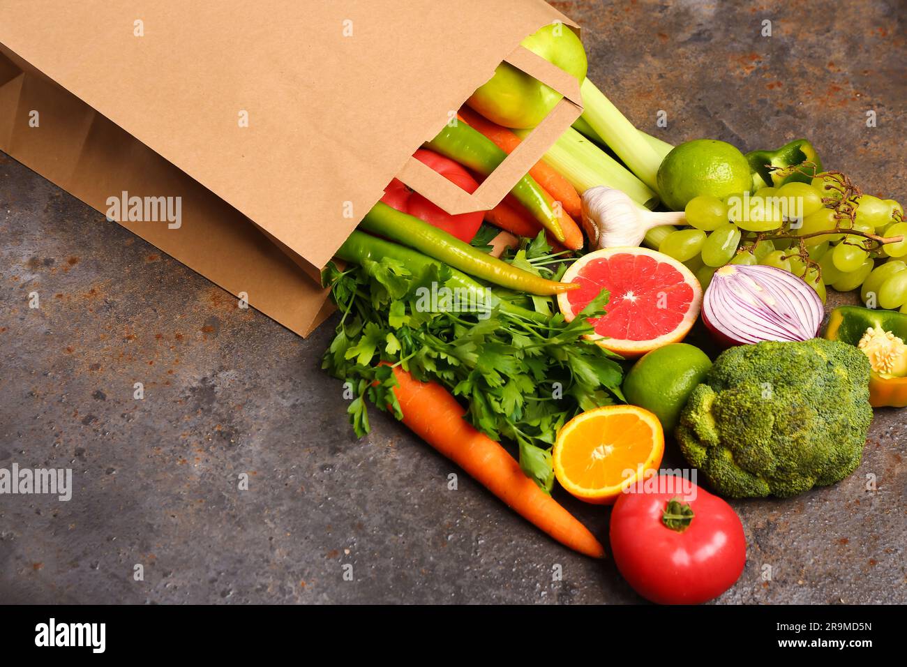 Paper bag with different fresh fruits and vegetables on dark background ...