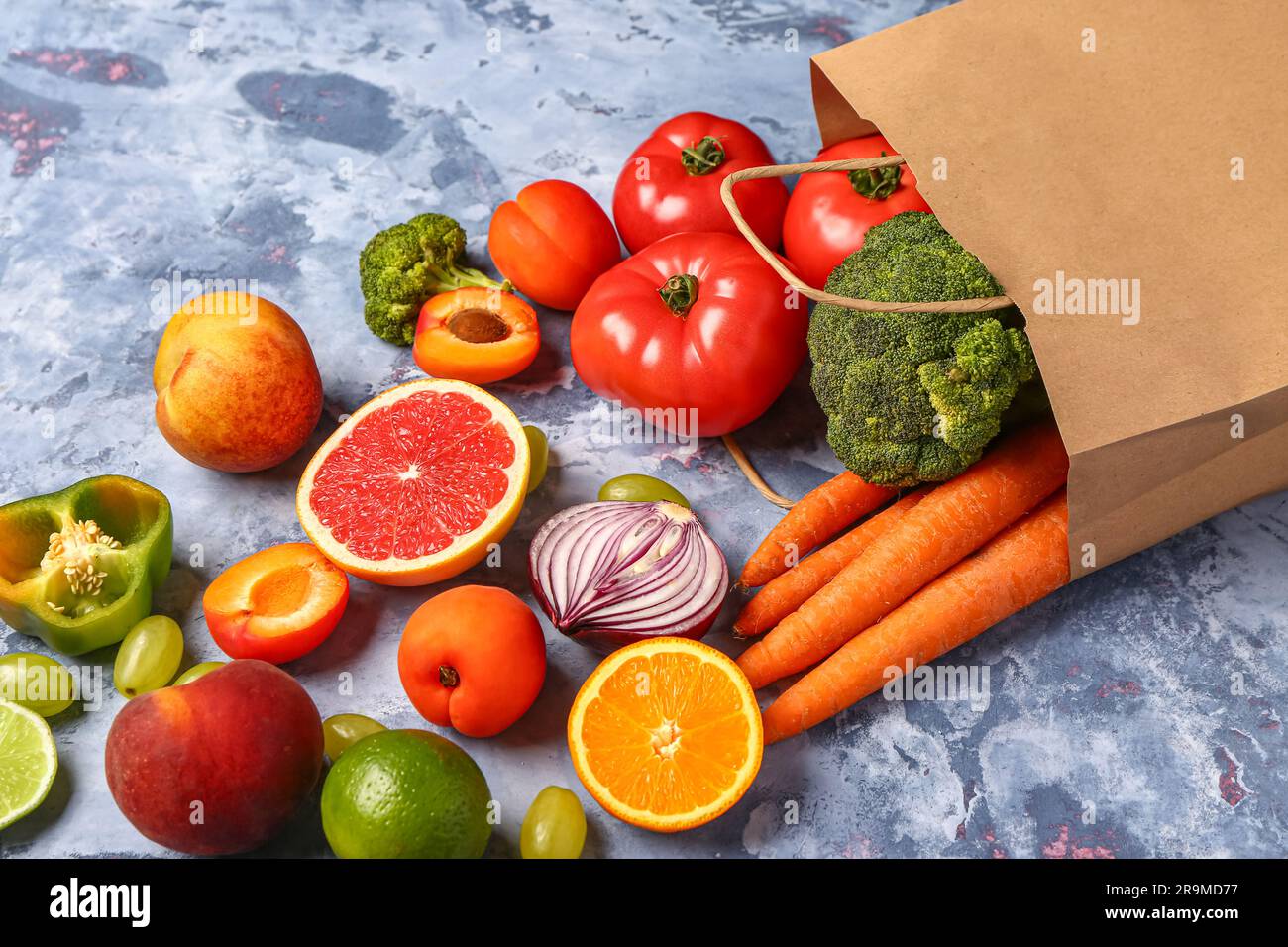 Paper bag with different fresh fruits and vegetables on blue background ...
