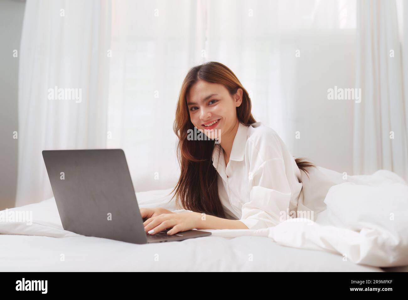 Happy smiling asian woman stretching on bed in the morning and using ...