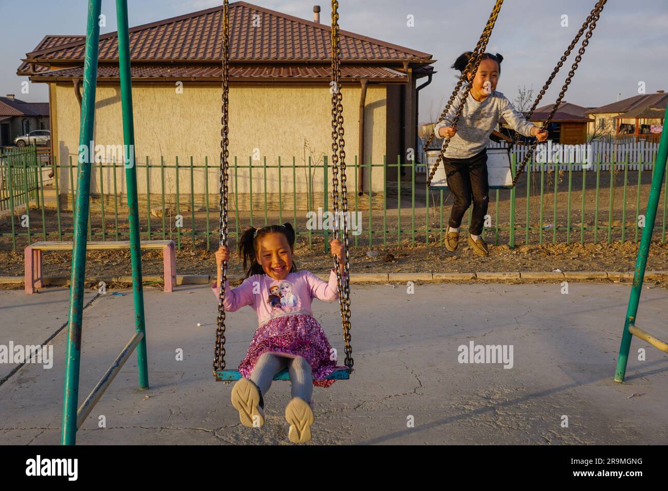 Sodgerel Ulziisaikhan, left, 6, and Sodbilig Ulziisaikhan, 8, swing at a playground in Dalanzadgad, Umnugovi province, Mongolia on March 30, 2023. (Uranchimeg Tsoghuu/Global Press Journal) Stock Photo