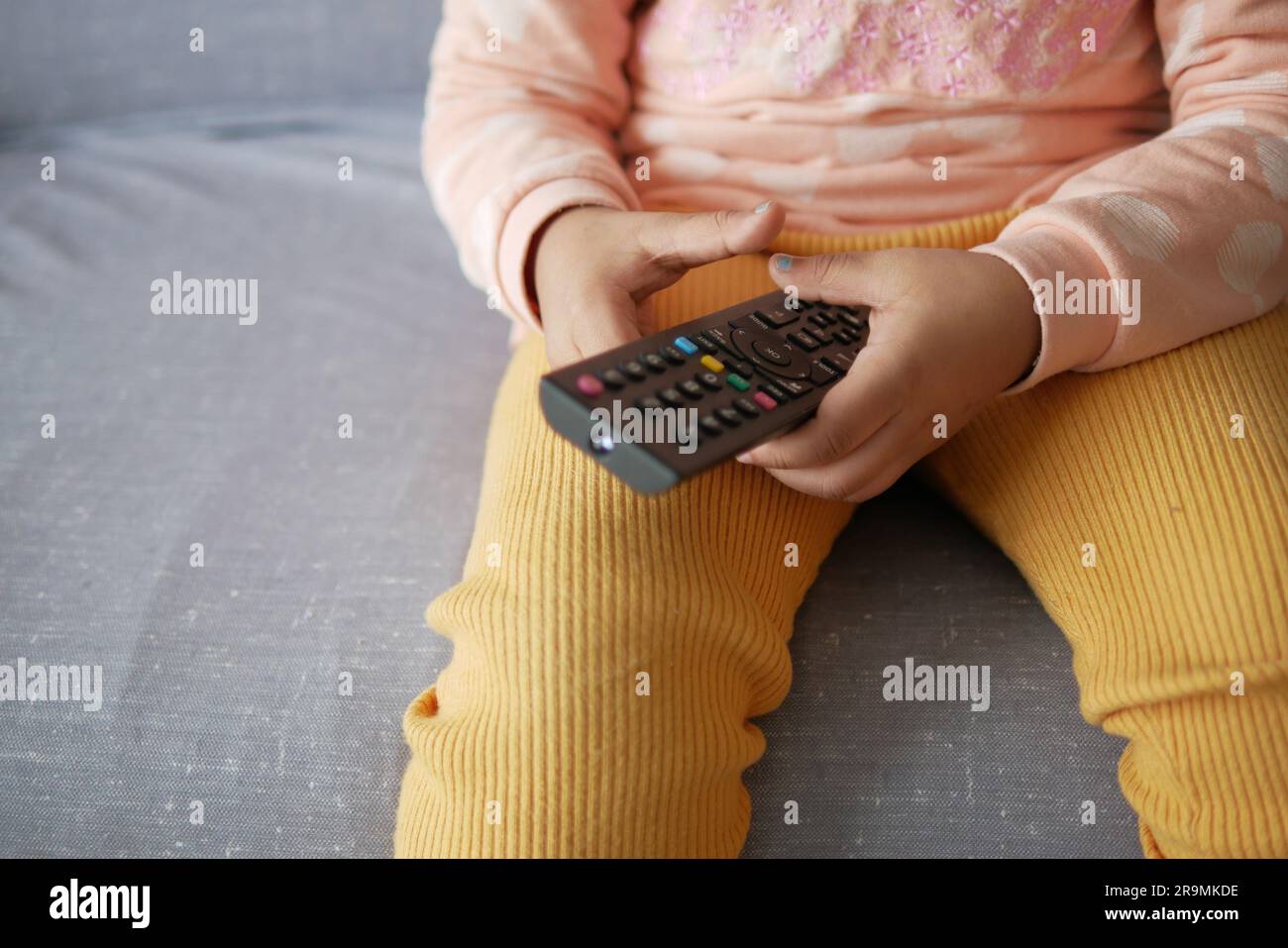child holding tv remote while sitting on sofa  Stock Photo