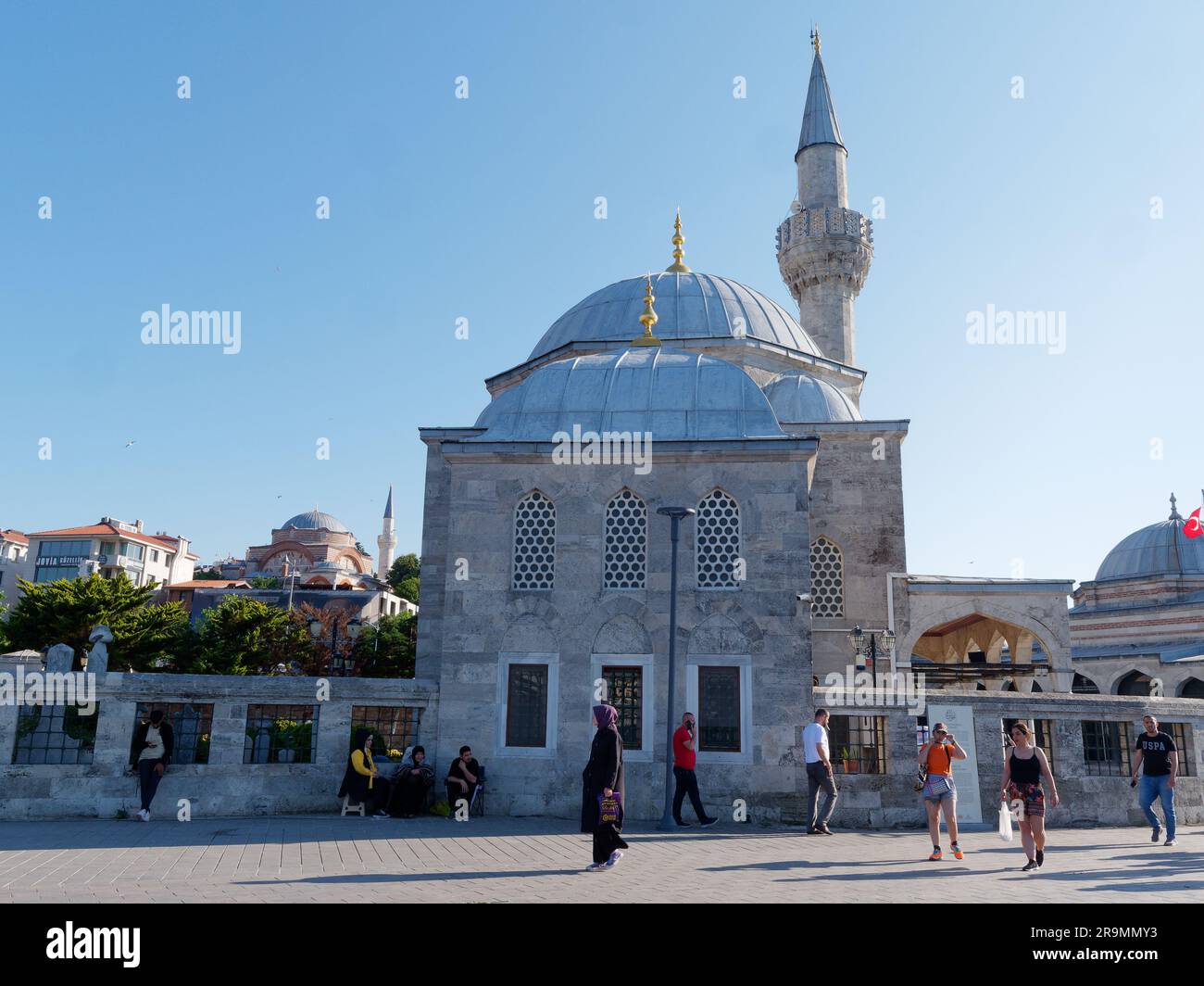 People in front of the small Şemsi Pasha Mosque, some taking shade on a summers day in the town of Uskudar, Istanbul, Turkey Stock Photo