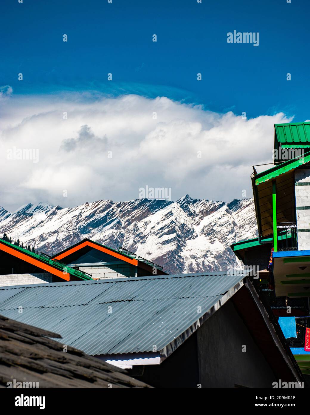 The colorful rooftops of quant village houses on the backdrop of majestic snowy mountain peaks Stock Photo