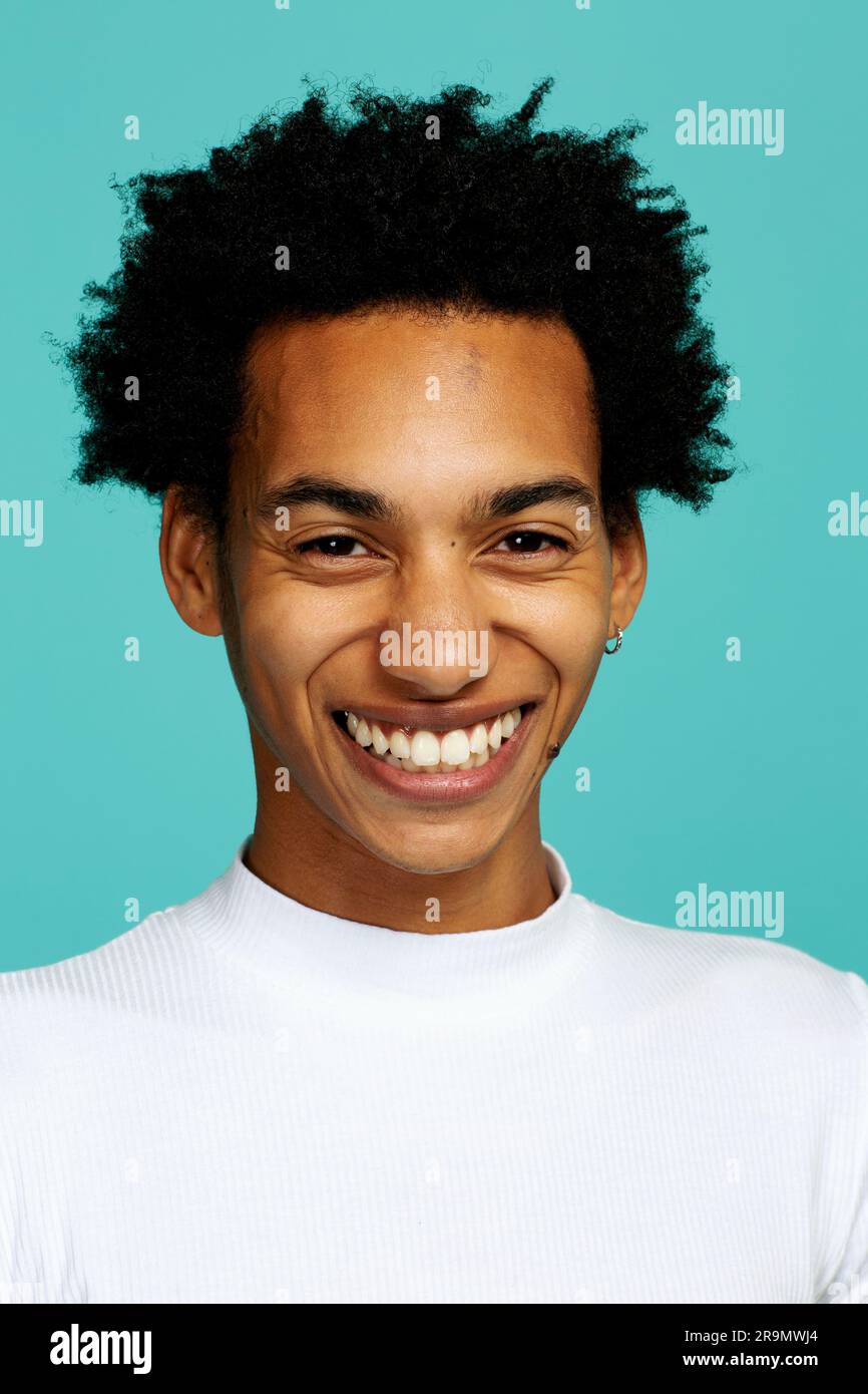 young adult man with afro hairstyle smiling, looking at camera, studio shot headshot Stock Photo