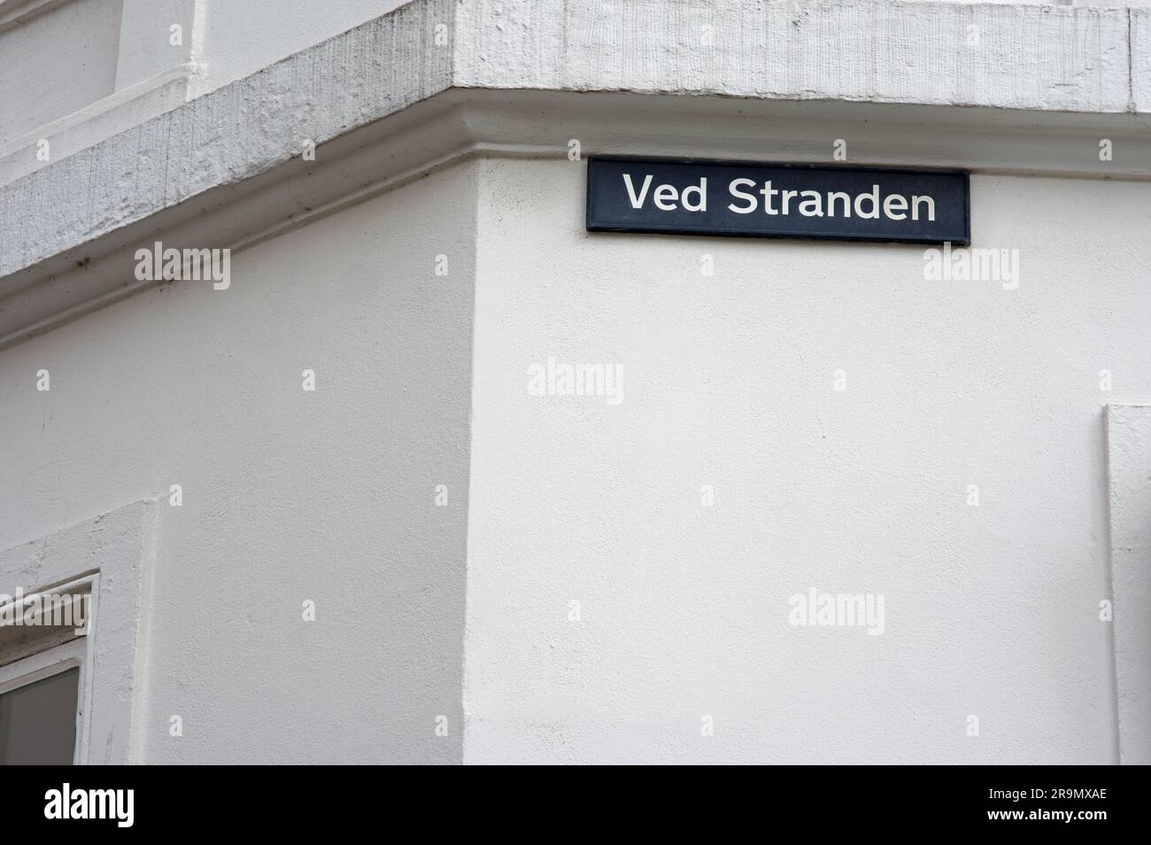 Blue street name sign of Ved Stranden on a white wall in the center of