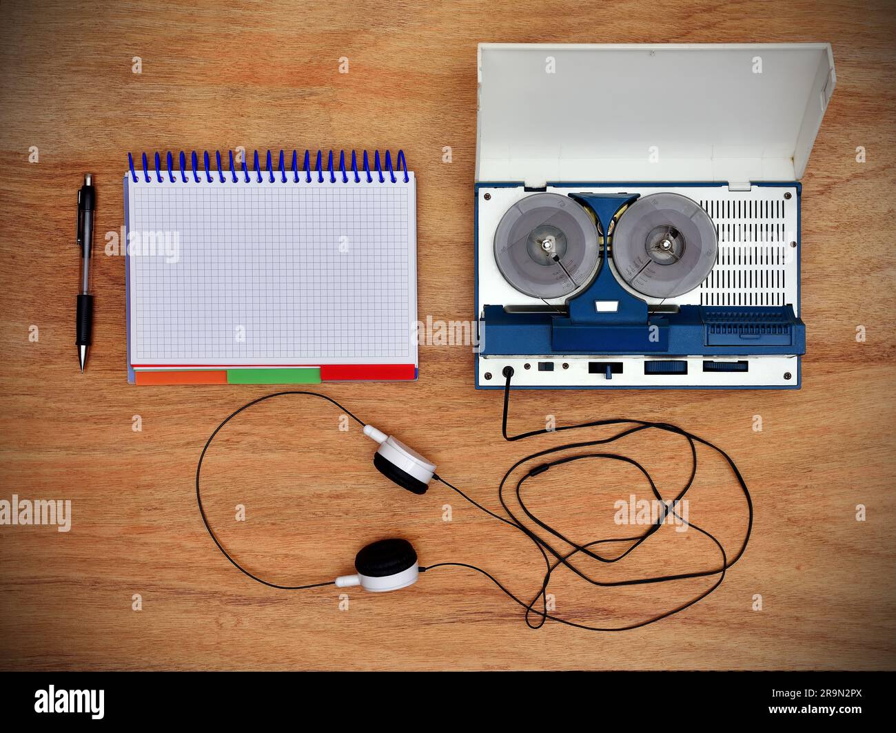 Reel tape recorder with headphones and blank notepad on wooden table. View from above Stock Photo