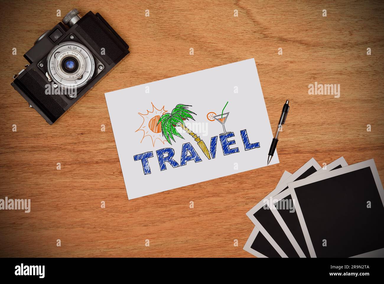 Camera and paper with drawing beach holiday concept. Work desk tourist. Stock Photo