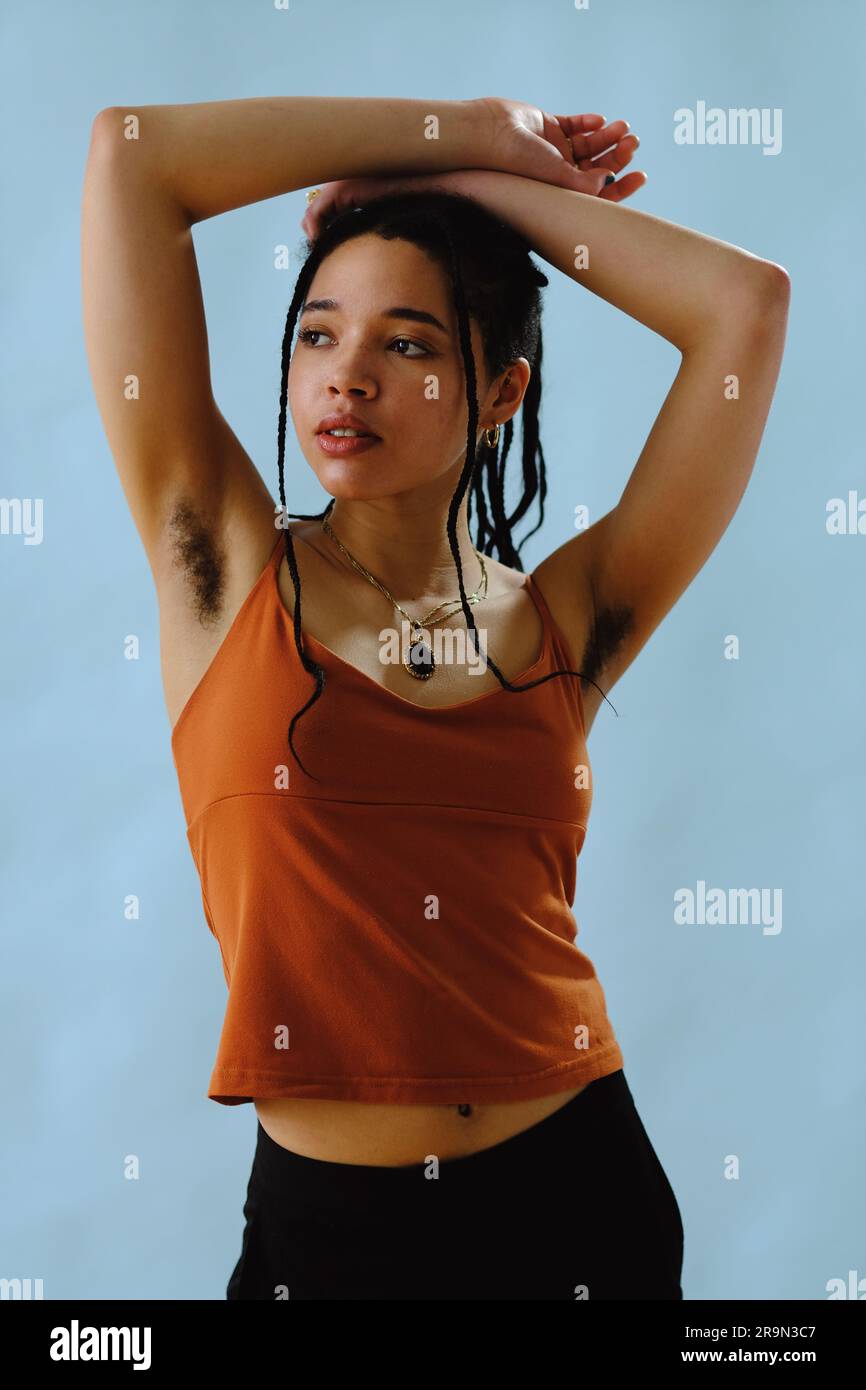 portrait of a young woman with arms raised and armpit hair, natural body Stock Photo