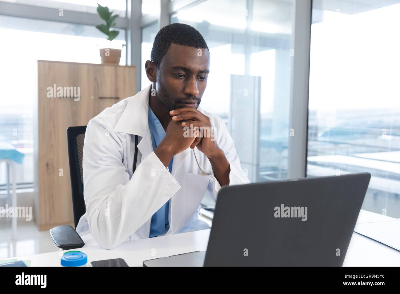 Unalt African american male doctor wearing lab coat and stethoscope, using ...