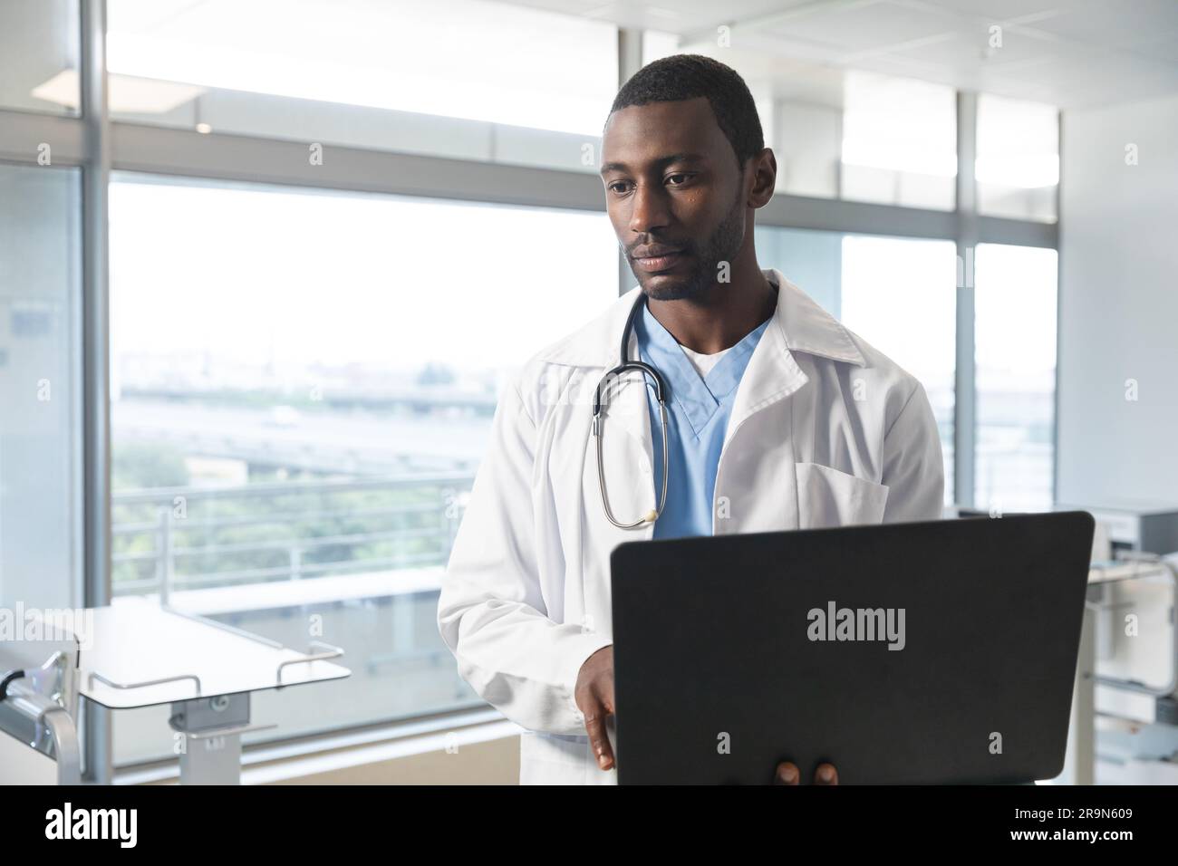 Unalt African american male doctor wearing lab coat and stethoscope, using ...