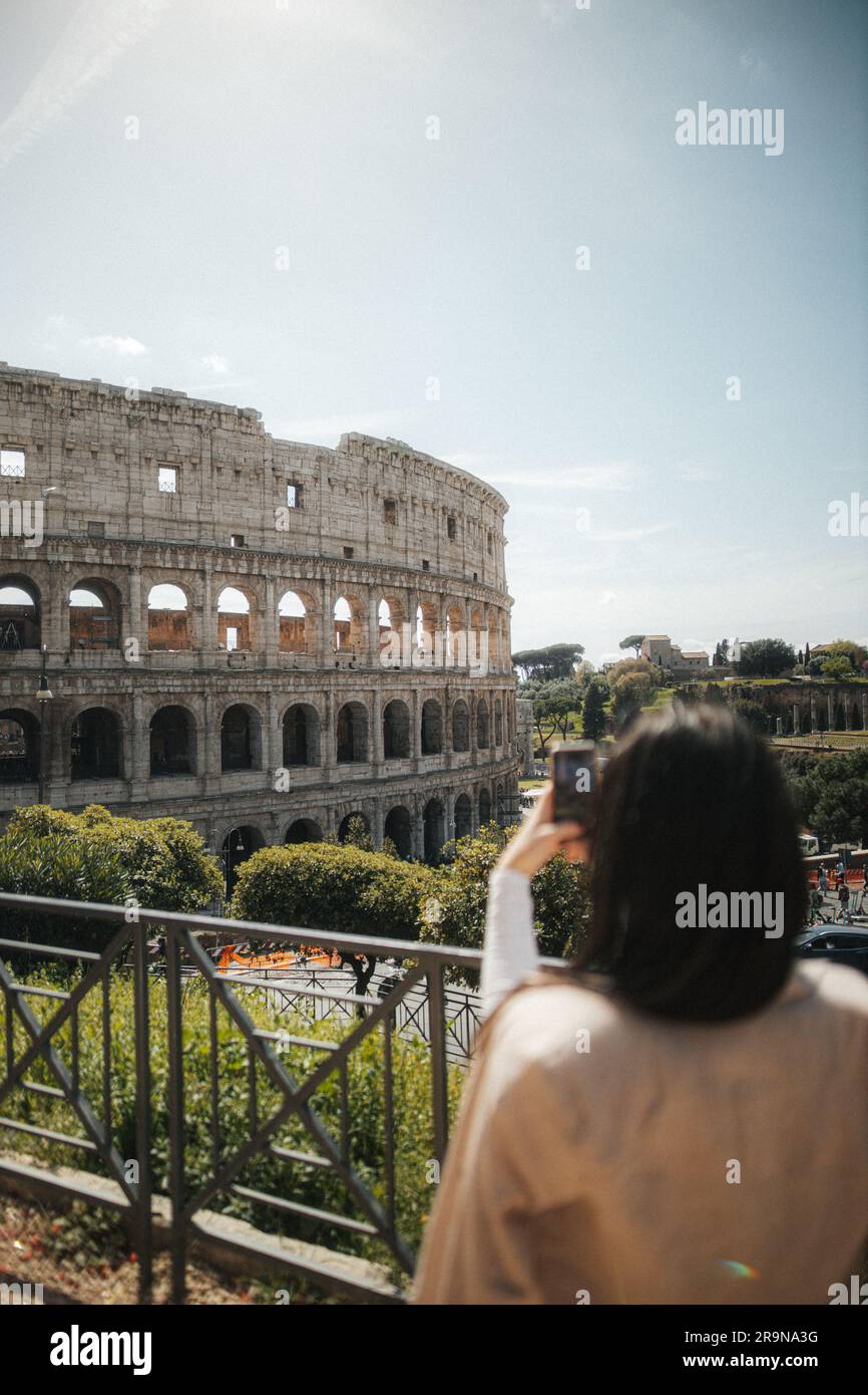 A young female photographer taking a picture of the iconic Colosseum in ...