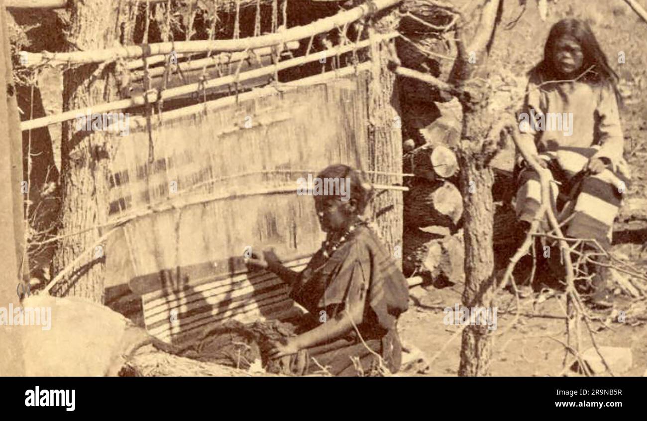 A vintage circa 1900 photo of Navajo Indians weaving at Canon de Chelle, (Canyon de Chelly } is entirely owned by the Navajo Tribal Trust of the Navajo Nation. It is the only National Park Service unit that is owned and cooperatively managed like this Stock Photo