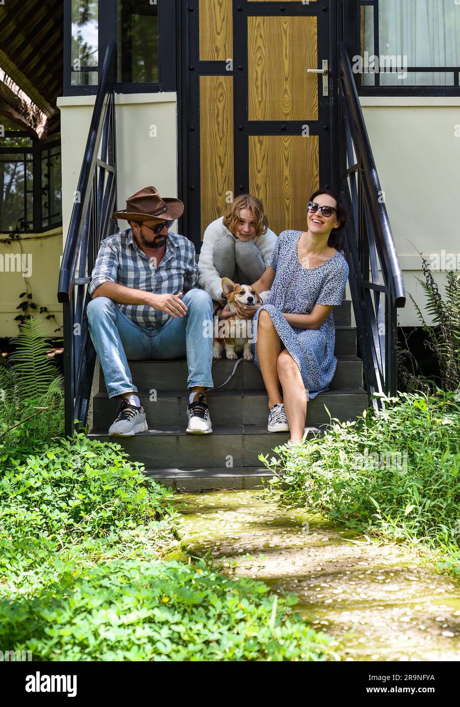 Family members father, mother and daughter sit on the porch of a their ...
