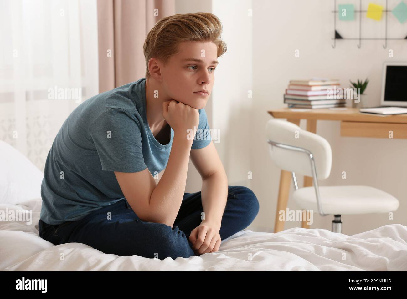 Upset teenage boy sitting on bed at home Stock Photo Alamy