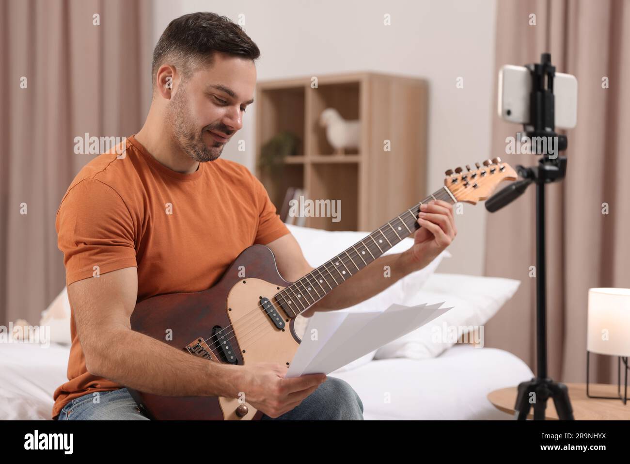 Music teacher tuning guitar while conducting online lesson at home. Time for hobby Stock Photo
