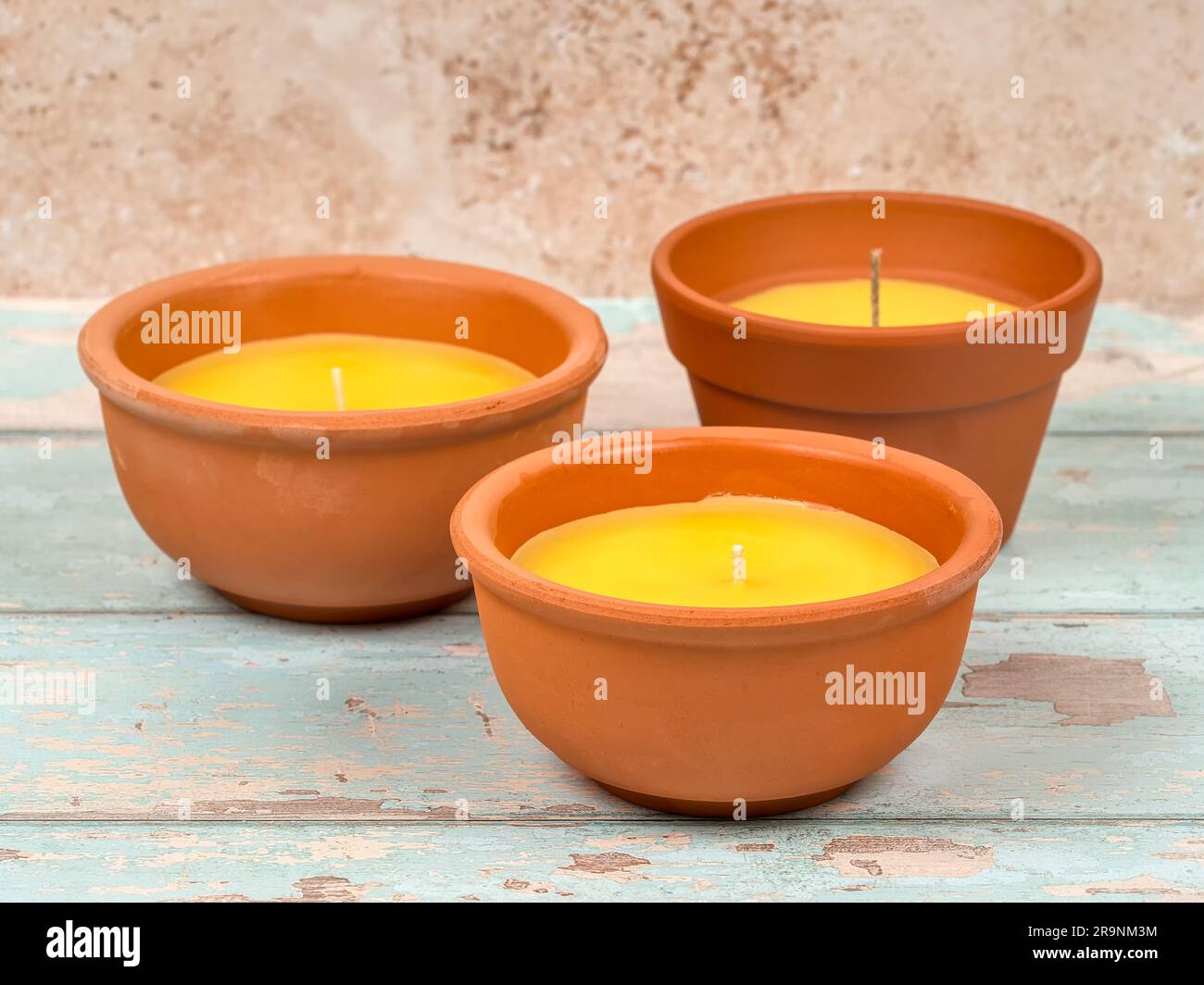Three citronella candles, new, in clay pots, on bright blue wooden background. A mosquito repellant for outdoor use. Stock Photo