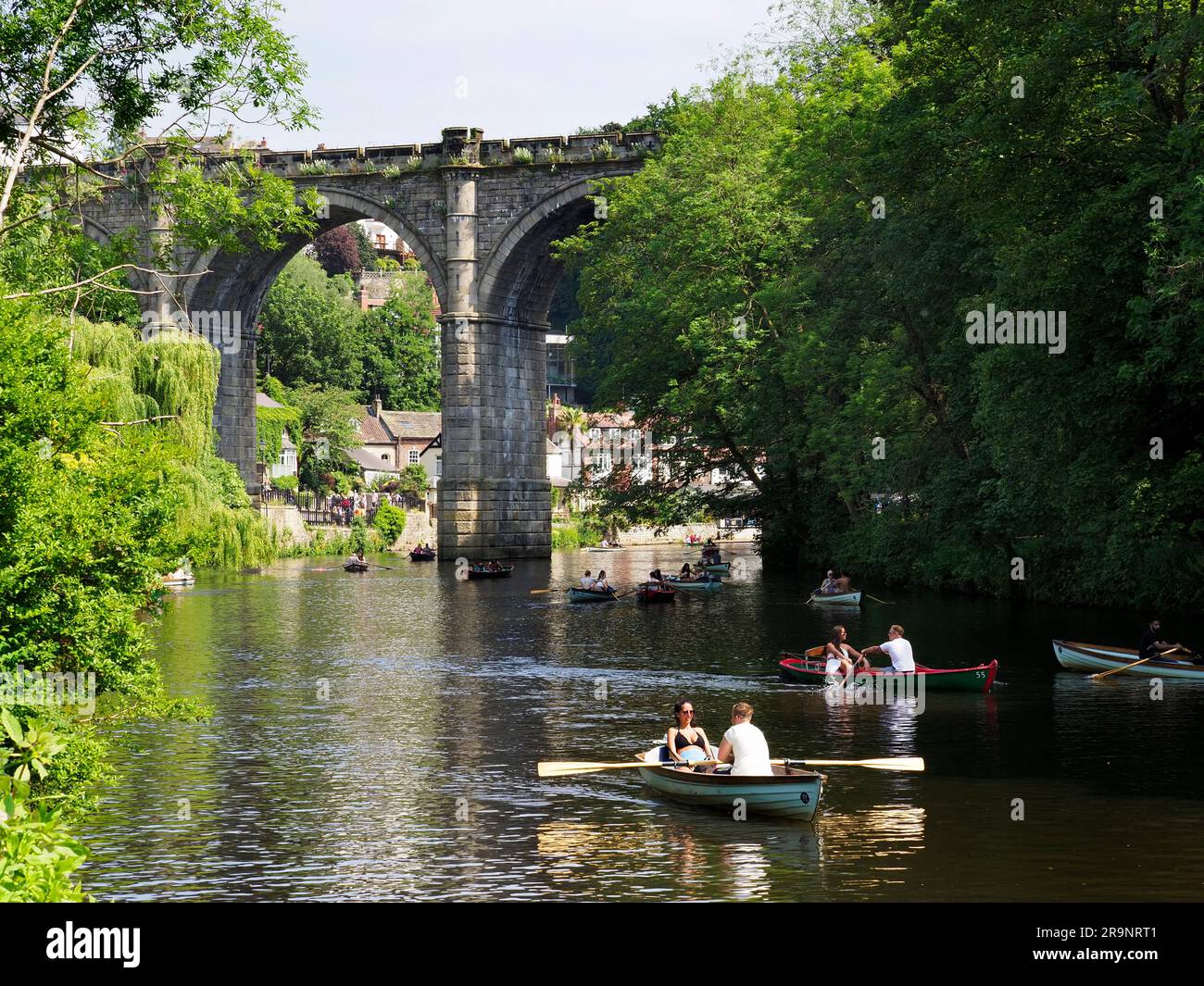 People rowing on the River Nidd below the railway viaduct on a sunny day at  Knaresborough North Yorkshire England Stock Photo