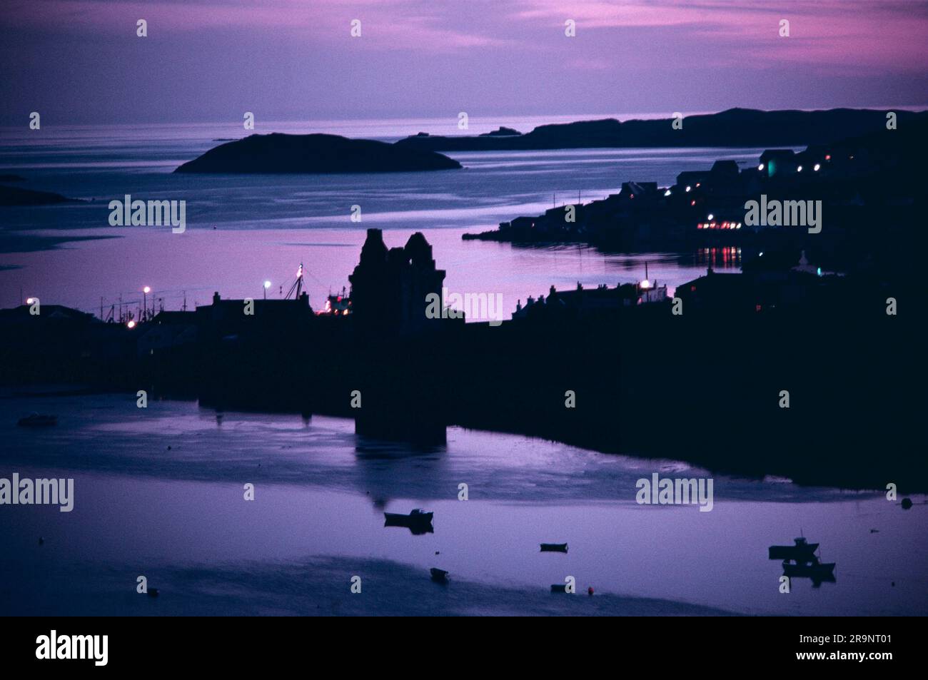 Scalloway, Mainland, Shetland Islands, Scotland circa 1995. The ruined Scalloway Castle at dusk, harbour and small fishing boats in profile. UK 1970S HOMER SYKES Stock Photo