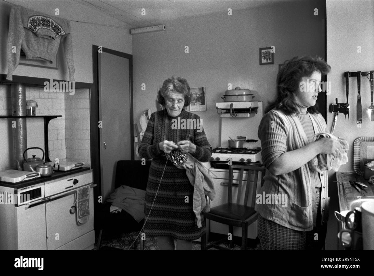 Knitting a Fair Isle Jumper. A crofting family, mother and daughter in their kitchen. The older woman is knitting a Fair Isle jumper, one has been washed and is hung up to dry over the stove, before being sold through a local shop. Shetlands Mainland, Shetland Islands, Scotland, circa 1979. UK 1970S HOMER SYKES Stock Photo