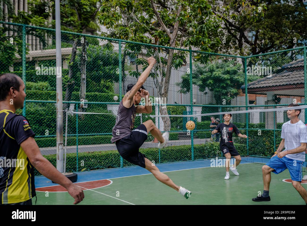 Local residents are seen playing Sepak Takraw at Benchasiri Public Park on Sukhumvit Road. Sepak Takraw also called kick volleyball or Thailand’s Acrobatic Volleyball is one of Southeast Asia’s most popular sports which is played with a ball made of rattan or synthetic plastic where the players are only allowed to touch the ball with their feet, body, or head. Stock Photo