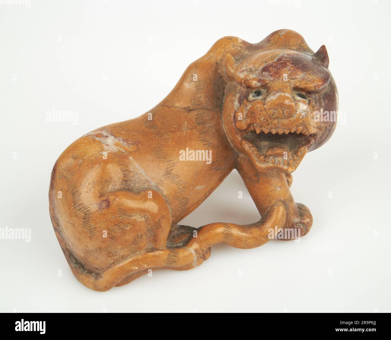 Antique Chinese hand carved stone lion on wooden stand Stock Photo