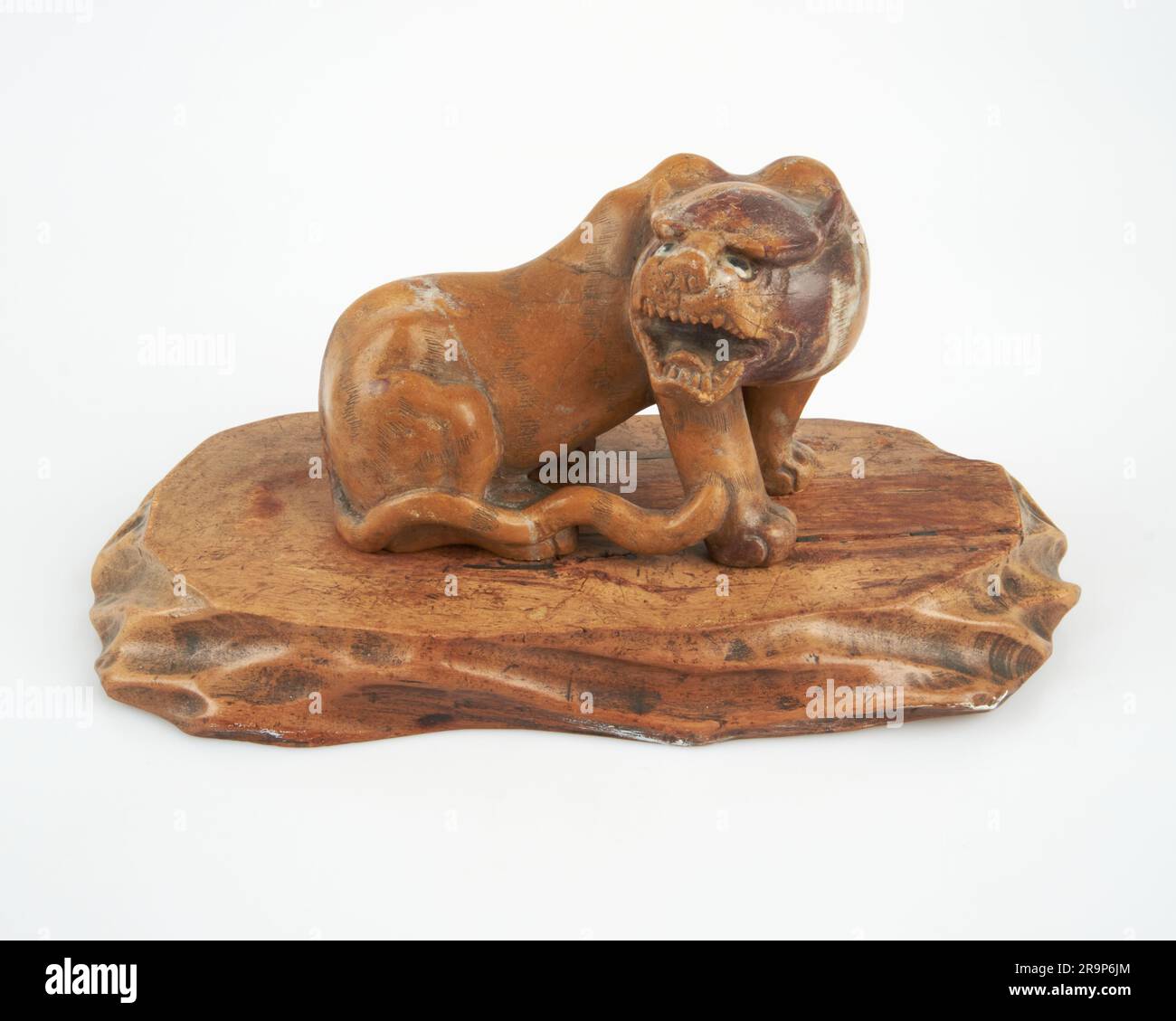 Antique Chinese hand carved stone lion on wooden stand Stock Photo