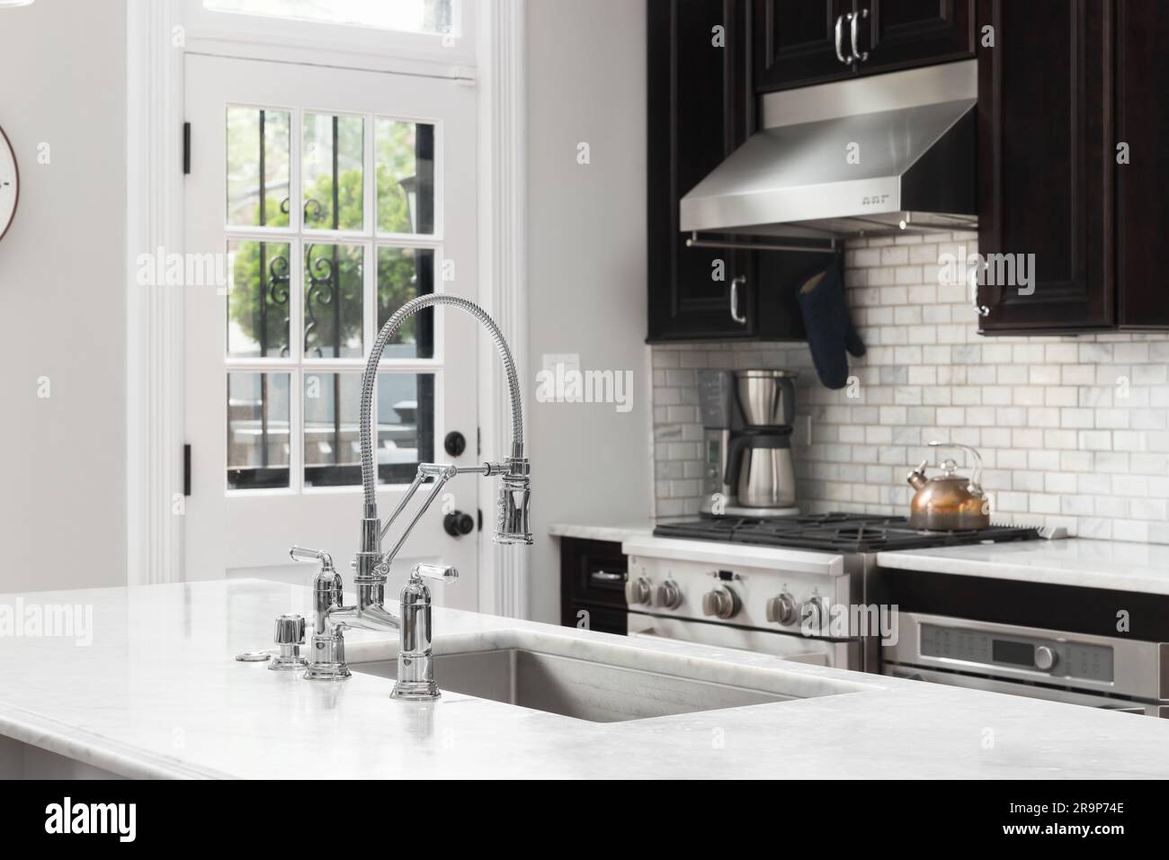 https://c8.alamy.com/comp/2R9P74E/a-kitchen-detail-with-a-chrome-faucet-dark-mahogany-cabinets-stainless-steel-appliances-and-a-marble-subway-tile-backsplash-2R9P74E.jpg