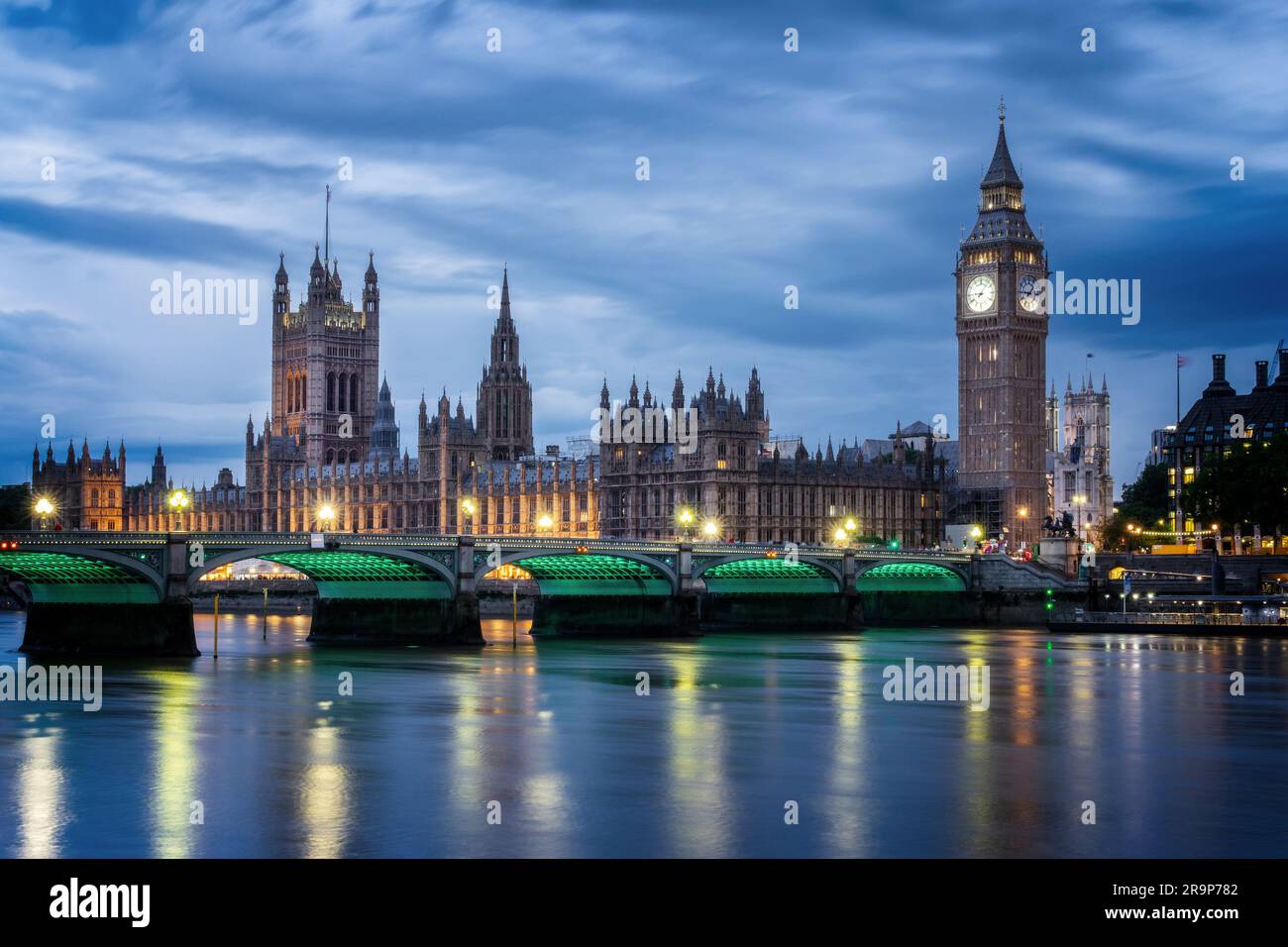 View of Westminster palace and bridge over river Thames with Big Ben illuminated at night in London, UK Stock Photo