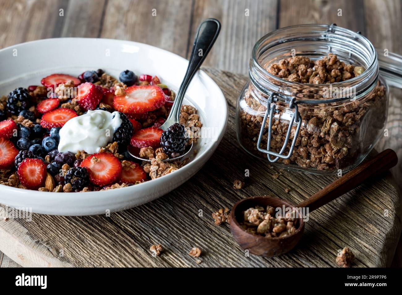 A healthy berry and granola cluster breakfast bowl topped with greek