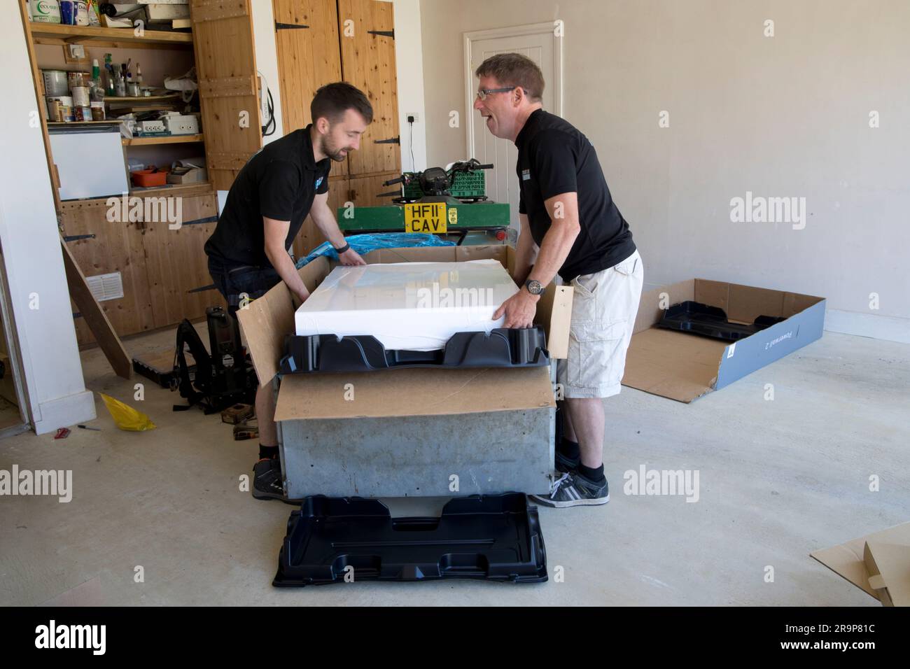 Two technicians unpacking Tesle 13.5kW Powerwall solar battery storage Colemans Hill Farm Mickleton UK Stock Photo