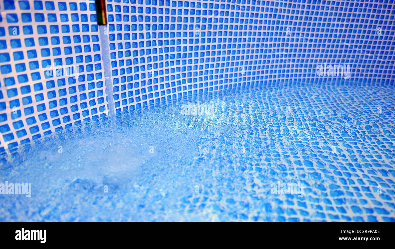 Water flowing from the hose into the pool filling. The inside of the swimming pool Stock Photo
