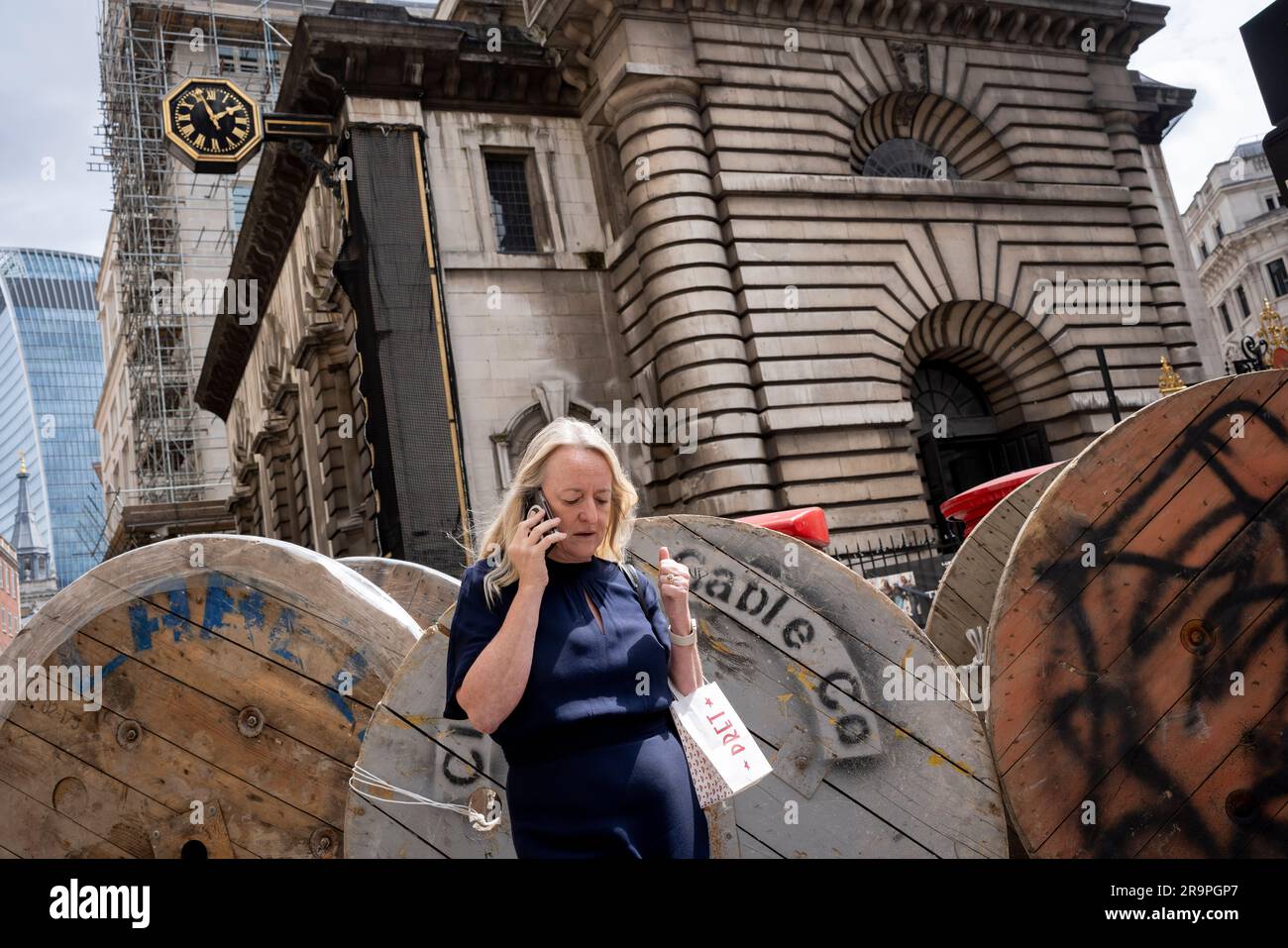 Passers-by and large cable reels by 'Cleveland Cable Company' during the installation of electricity cable into premises on Lombard Street in the City of London, the capital's financial district, on 27th June 2023, in London, England. Cleveland Cable Company is a global cable and cable accessory supplier. Stock Photo