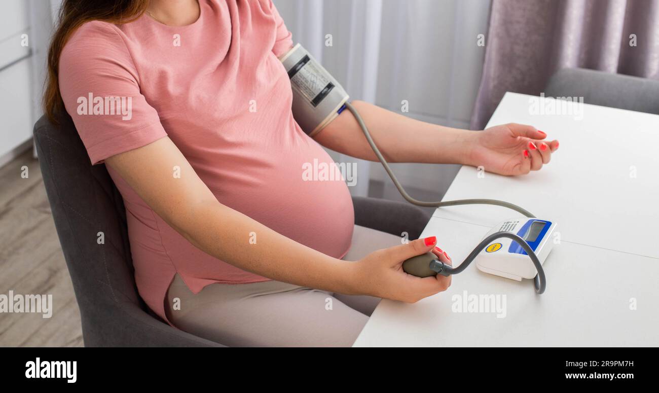 A pregnant girl measures blood pressure with a device. The concept of