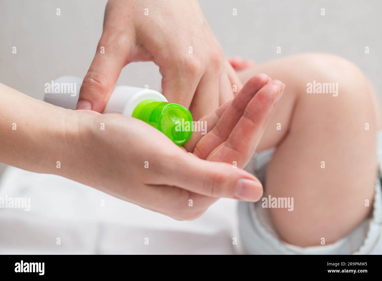 The mother applies a moisturizing cream with oil to the baby's skin so that the body does not become dry. Hygiene and skin care of the newborn, close- Stock Photo