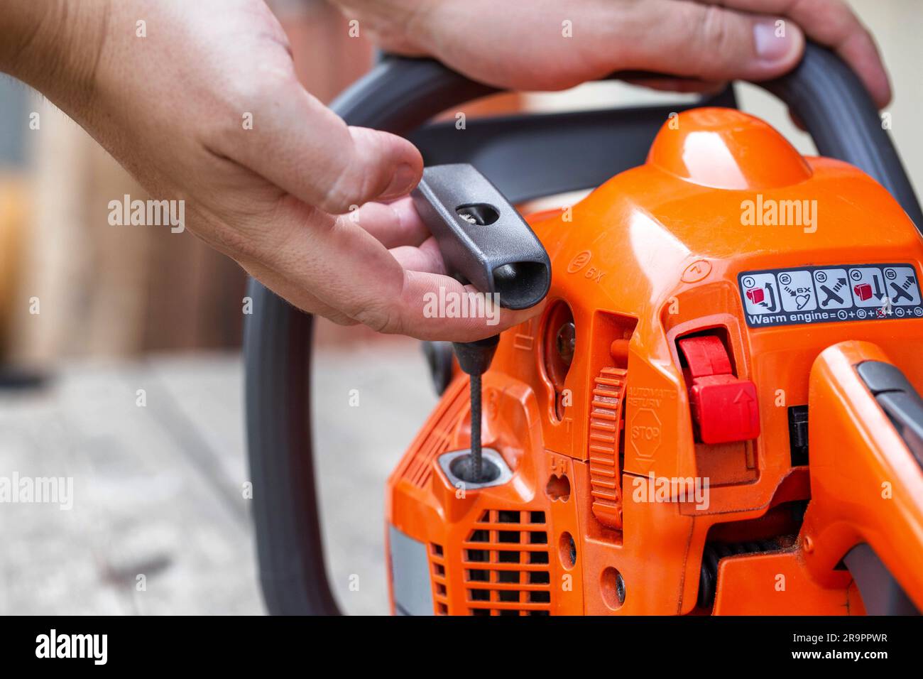 The process of starting a chainsaw. A male worker pulls the starting
