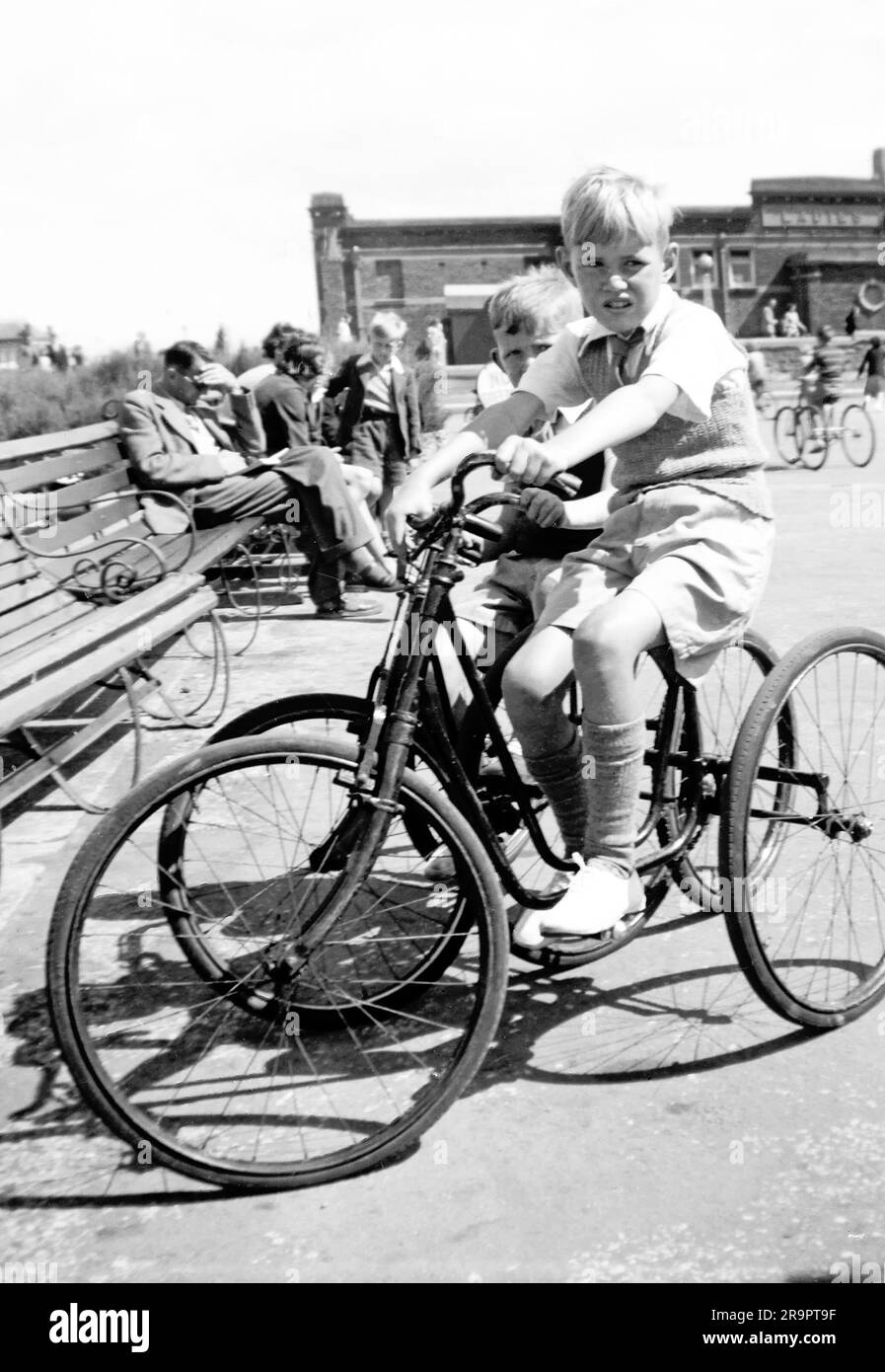 Historical archive year 1950 view of seaside bike hire playground where three wheel pedal cycles were loaned to young holiday makers with this eight year old boy at front of this image the only person covered by a model release at postwar Rhyl seaside town in Denbighshire North Wales UK. Note, no other model or property releases are available. Stock Photo
